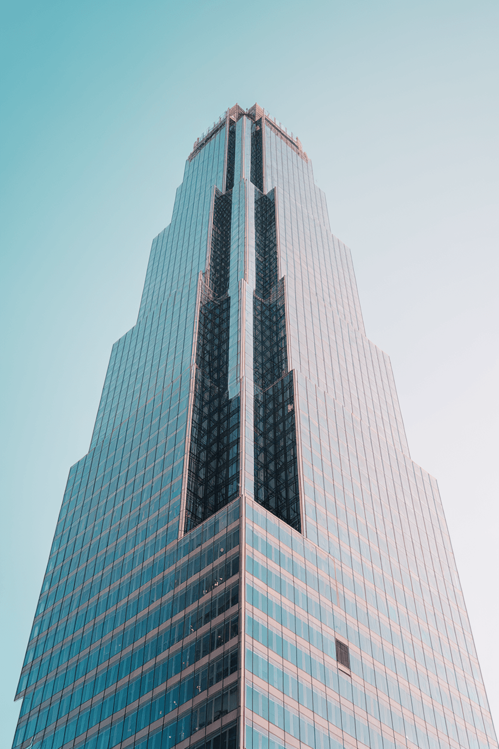 Glass skyscraper facade reflecting a clear blue sky